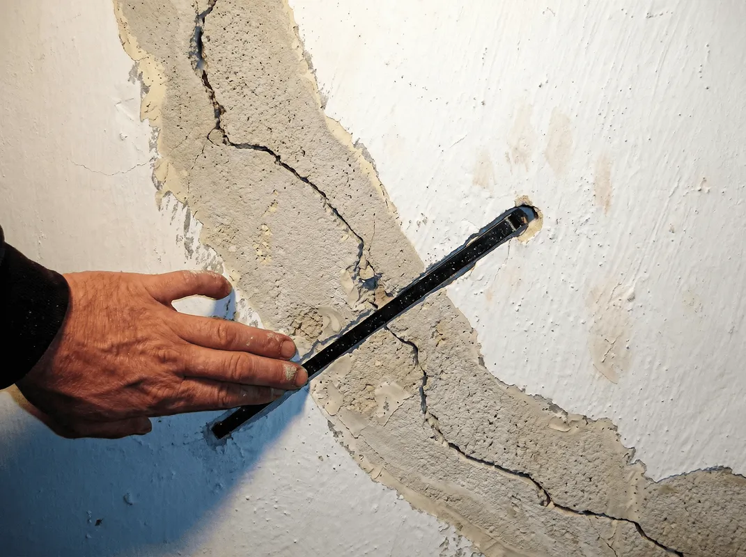 A wall with a large crack is being inspected by a professional in Jacksonville, FL